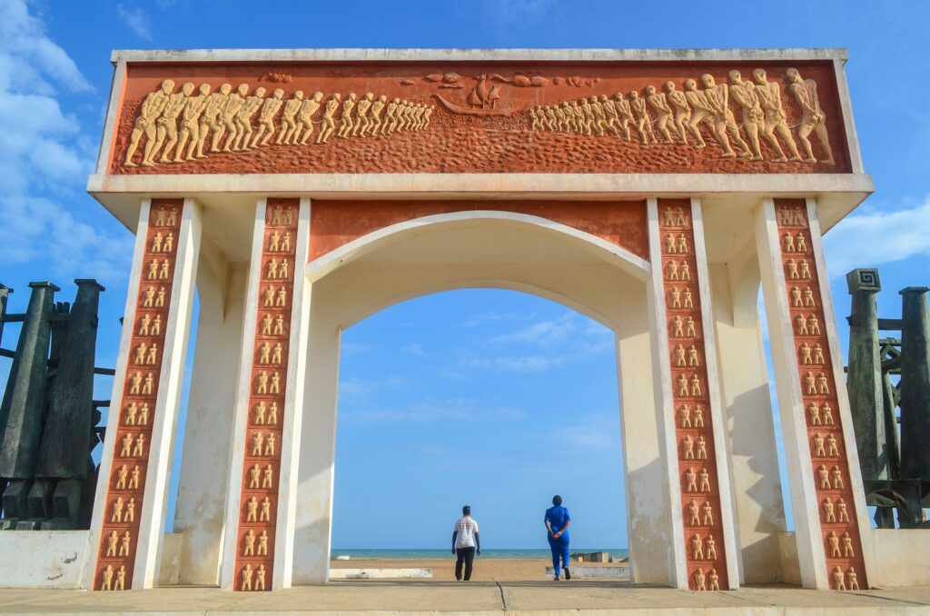 Ouidah’s Door of No Return memorial arch on the beach in Benin — a concrete gateway symbolizing the Atlantic slave trade.