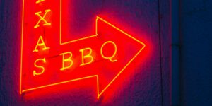 Neon sign for Texas BBQ glowing in red and yellow — symbolic of Southern food culture and Juneteenth celebration.