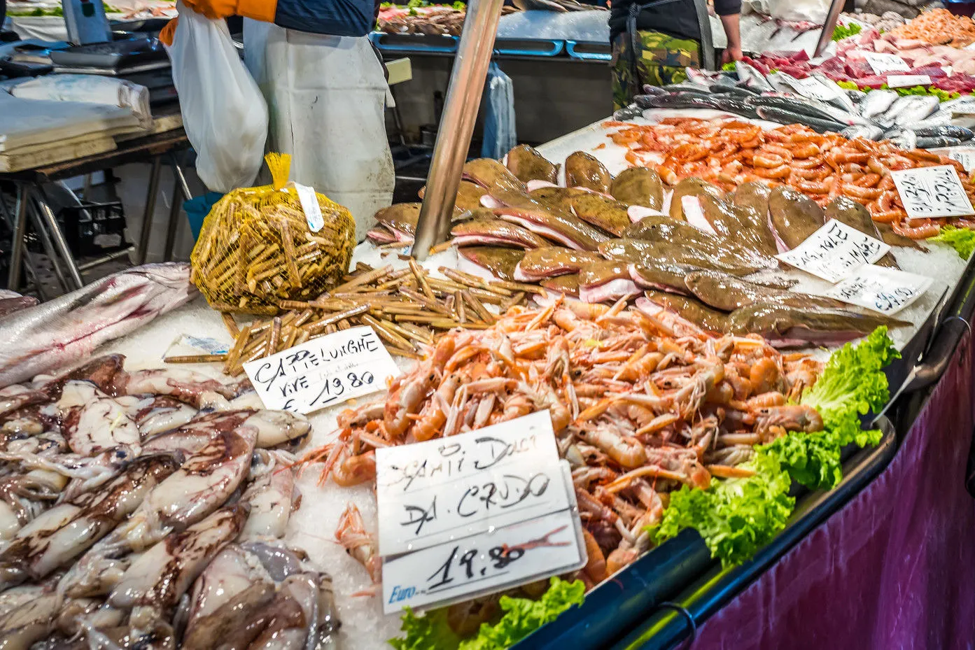 Fresh seafood on display at Rialto Fish Market in Venice, featuring shrimp, squid, and local fish varieties