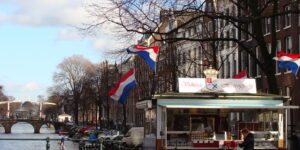 A herring stand by an Amsterdam canal with boats in the background — a classic scene from the city’s street food culture, as featured in Somebody Feed Phil Season 8.