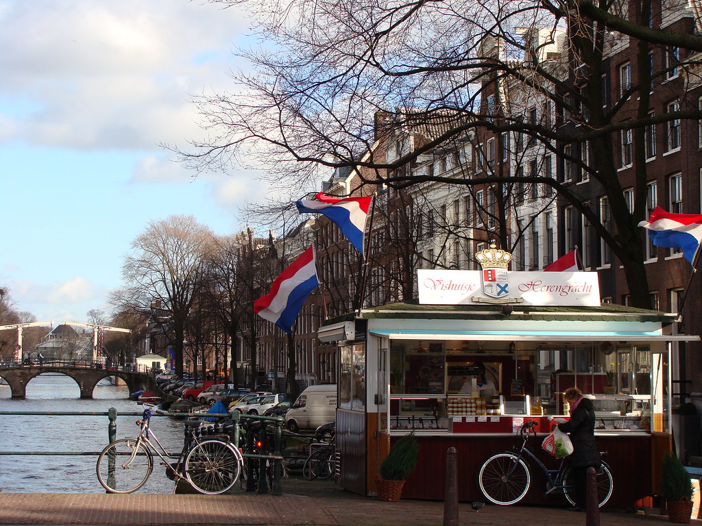 A herring stand by an Amsterdam canal with boats in the background — a classic scene from the city’s street food culture, as featured in Somebody Feed Phil Season 8.