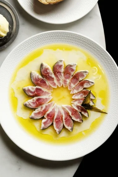 Sliced blue mackerel with olive oil served alongside sourdough and butter at a fine dining seafood restaurant in Sydney.