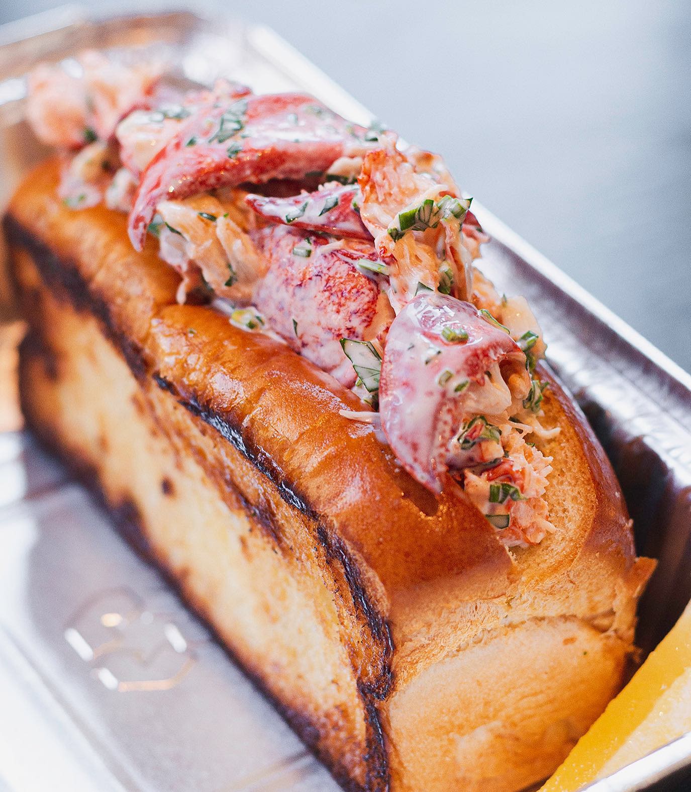 Boston-style lobster roll overflowing with fresh lobster chunks, served with melted butter.