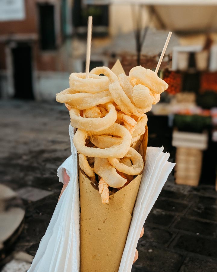 Street food in Venice featuring fried calamari and shrimp served in a yellow paper cone