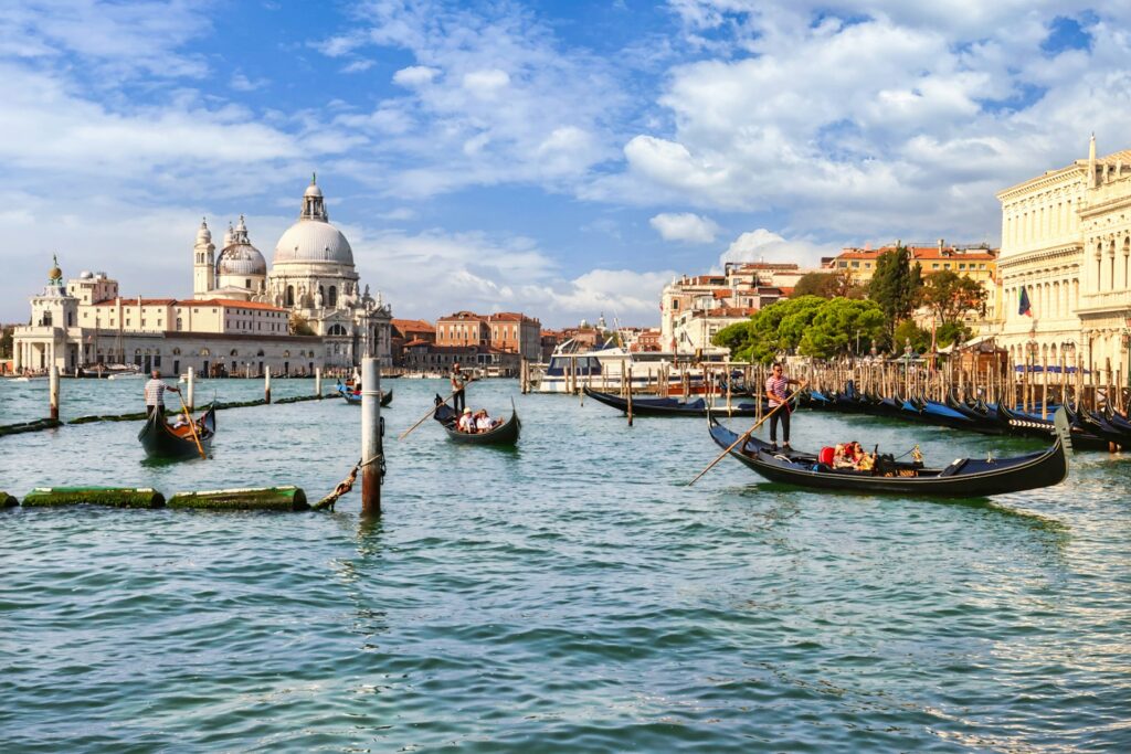 Gondolas floating on the Grand Canal in Venice with the domed Basilica di Santa Maria della Salute in the background, capturing the city’s iconic waterways and architecture featured in Stanley Tucci’s Italy journey.