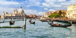 Gondolas floating on the Grand Canal in Venice with the domed Basilica di Santa Maria della Salute in the background, capturing the city’s iconic waterways and architecture featured in Stanley Tucci’s Italy journey.
