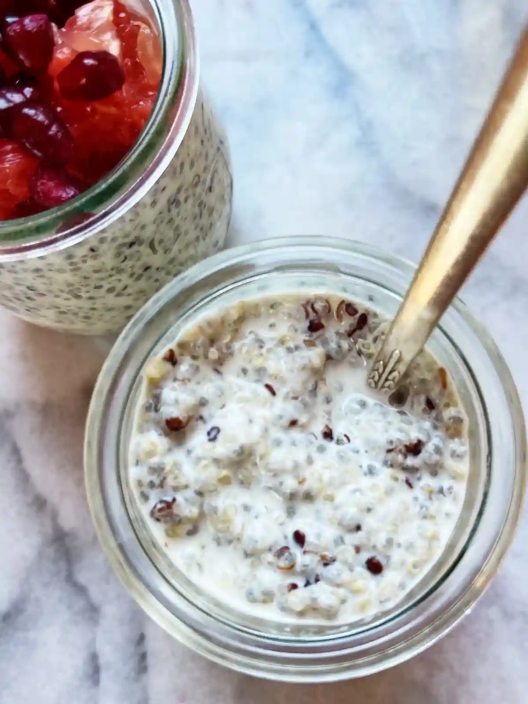 Glass jars filled with overnight quinoa and chia pudding topped with grapefruit and pomegranate seeds.