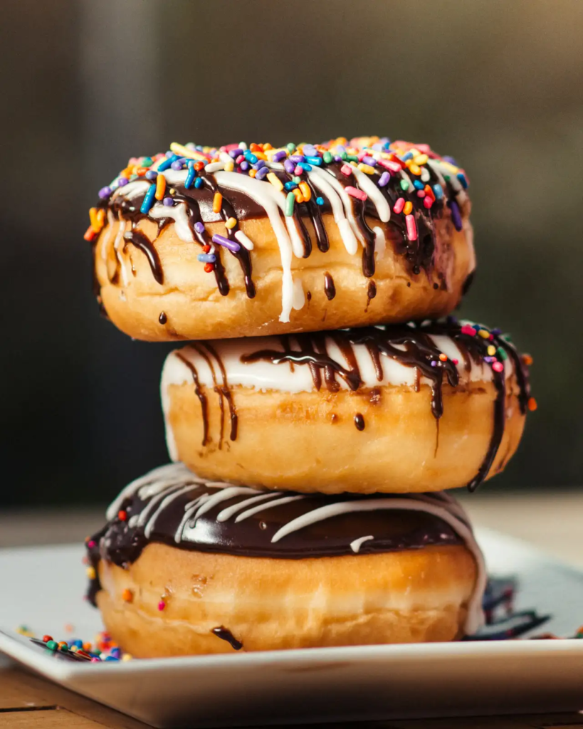 Stack of frosted donuts topped with rainbow sprinkles — a classic sugary breakfast option.