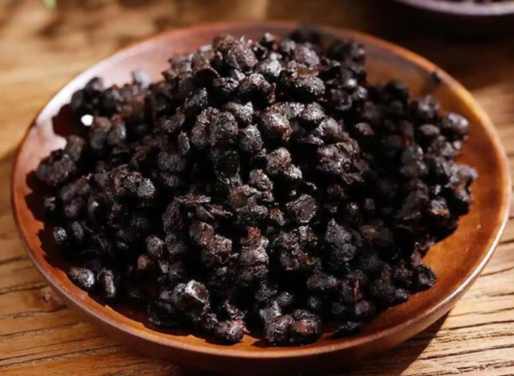 Close-up of douchi, fermented black soybeans on a wooden plate, a historic Chinese condiment.