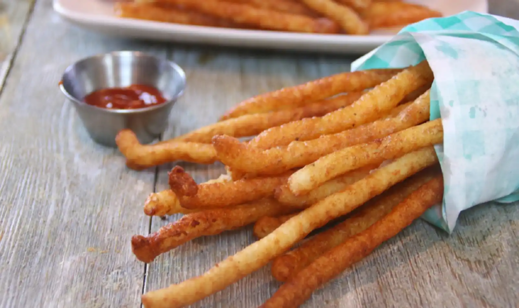 Extra-long, golden brown fries served in a paper wrap with ketchup.
