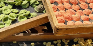 Colorful orecchiette pasta drying in the sun on wooden trays in Bari, Italy