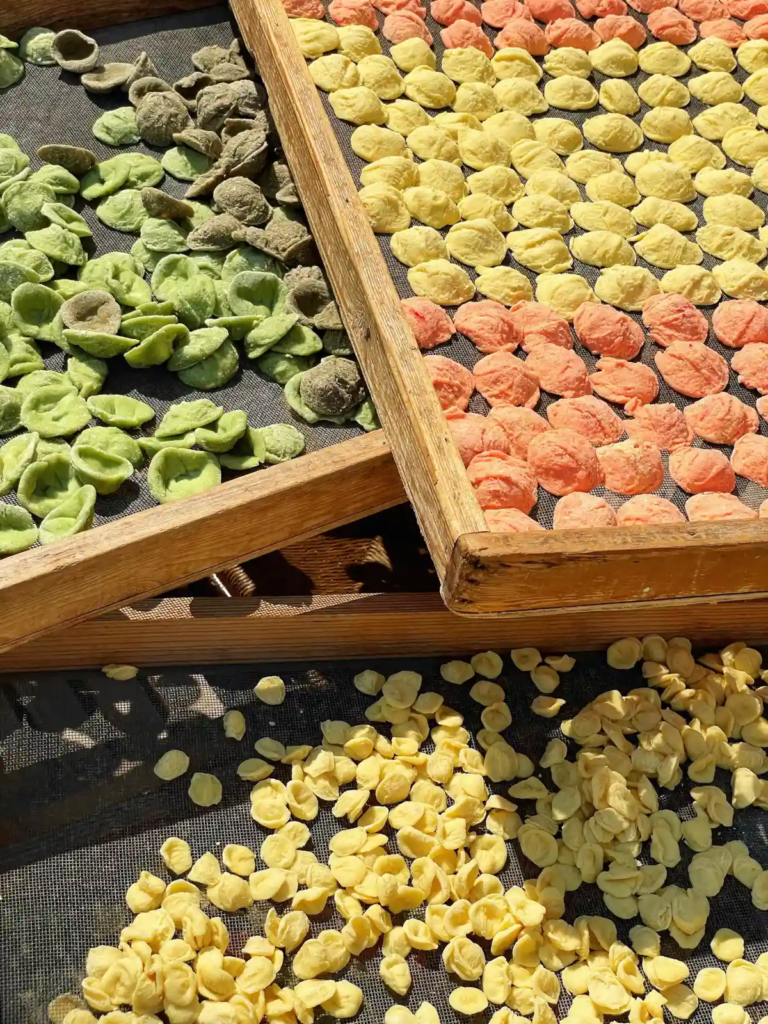 Colorful orecchiette pasta drying in the sun on wooden trays in Bari, Italy