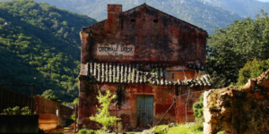 Old rural building with “Orientale Sarda” sign nestled in the mountains of Sardinia, Italy