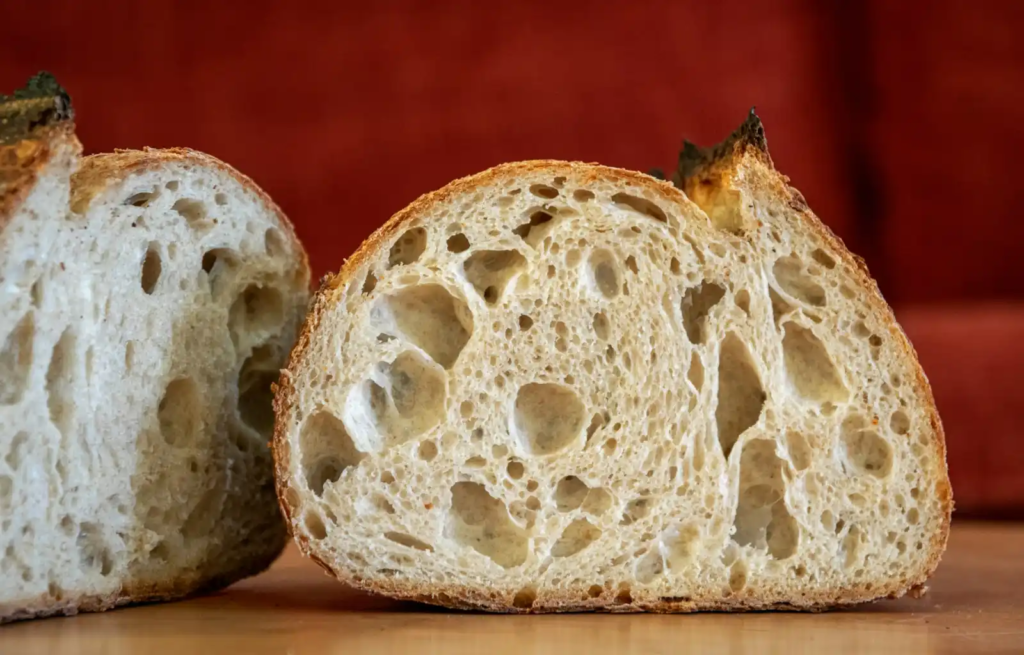 A sliced sourdough loaf showing natural air pockets from fermentation.