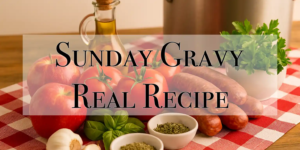 Ingredients for Sunday Gravy—including red apples, tomatoes, Italian sausage, herbs, garlic, and olive oil—arranged on a red checkered tablecloth with a cooking pot in the background.