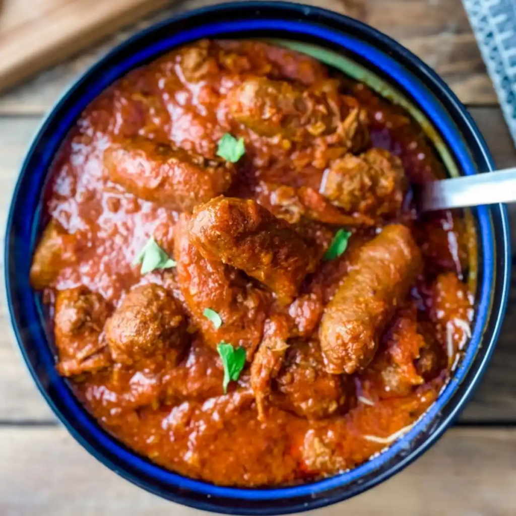 Close-up of Sunday Gravy with meatballs and sausages in a bowl of rich red sauce from movie Nonnas.