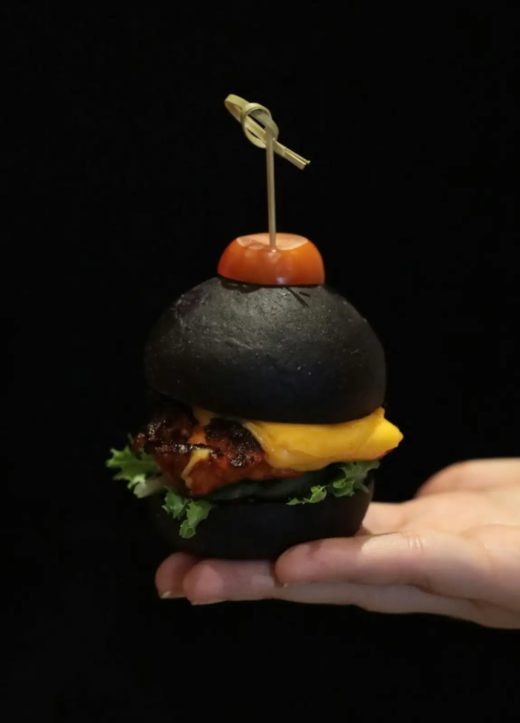 Charcoal burger with dark bun, lettuce, tomato, and patty