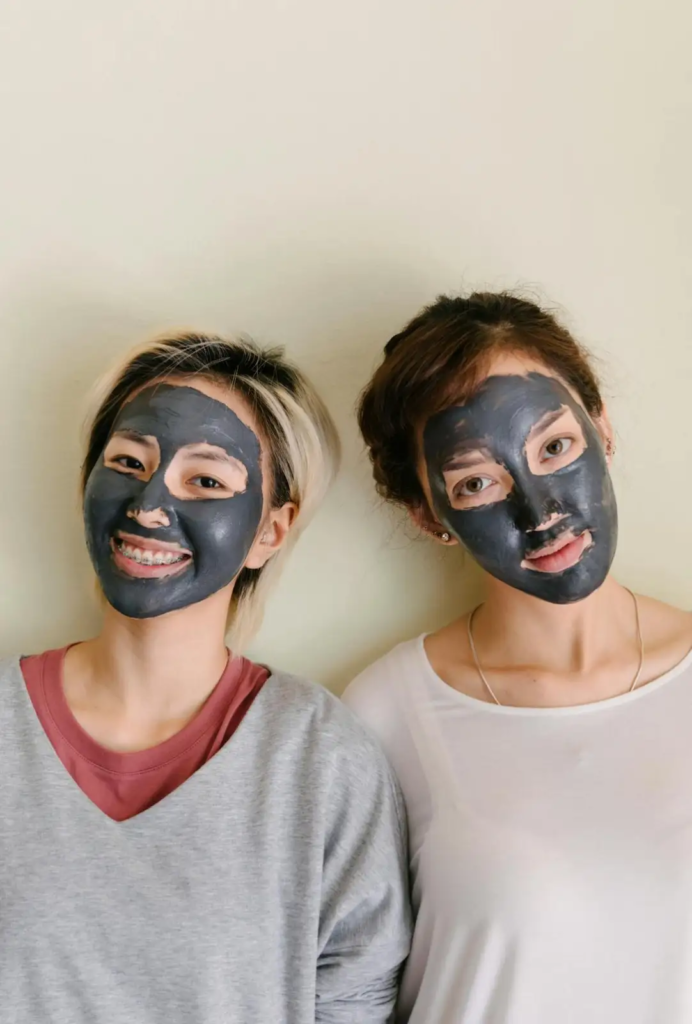 Two women wearing black charcoal face masks