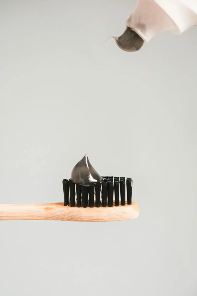 Tube of charcoal toothpaste on bamboo toothbrush