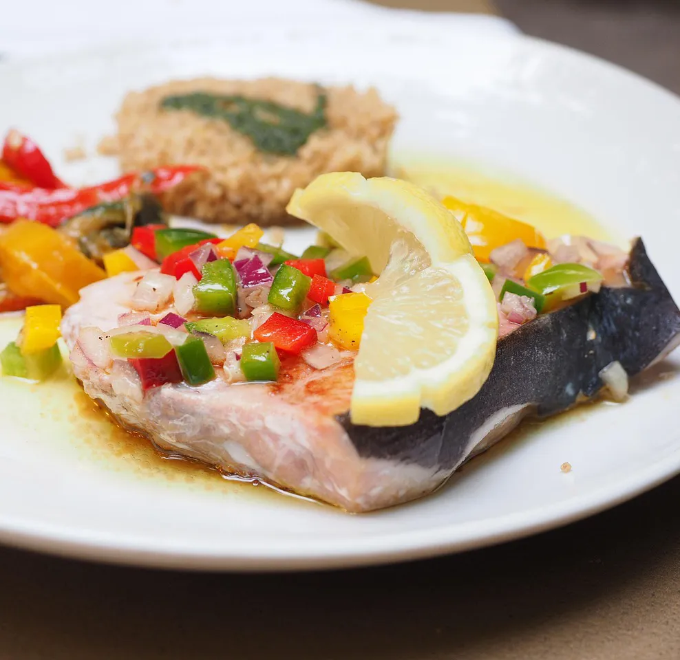 Grilled swordfish fillet topped with chopped vegetables and lemon, served in Calabria, Italy