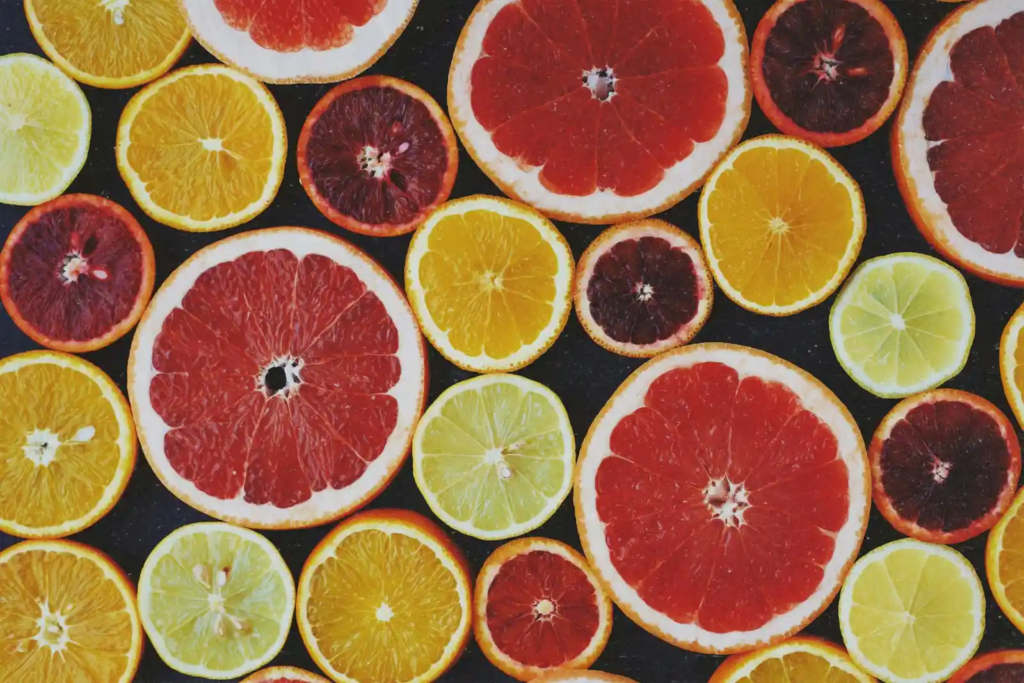 An assortment of sliced citrus fruits including oranges, grapefruits, limes, and lemons, arranged in an overlapping pattern.