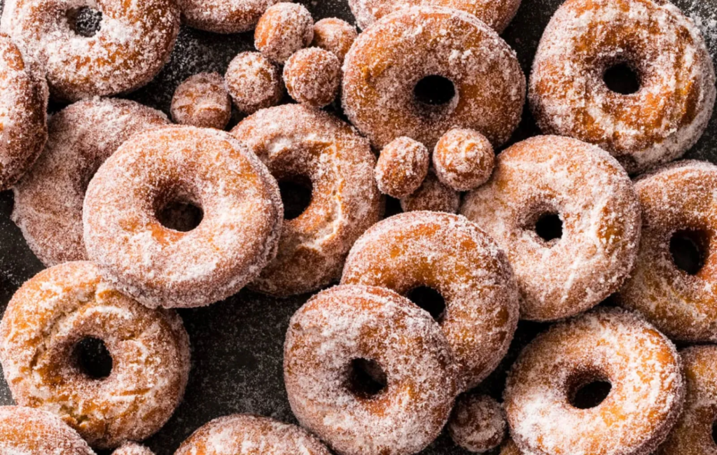 Cinnamon-sugar apple cider donuts and donut holes piled together.
