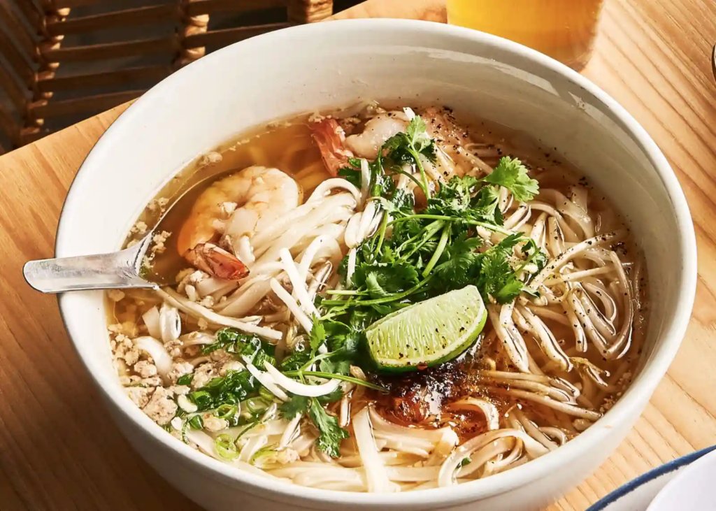 Close-up of two bowls of Kuy Teav Phnom Penh noodle soup being served.