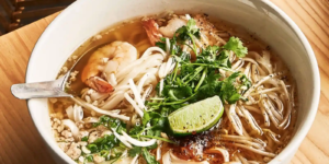 Close-up of two bowls of Kuy Teav Phnom Penh noodle soup being served.