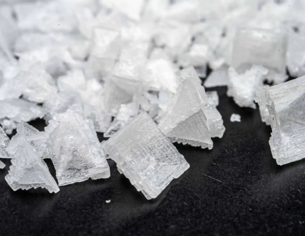 Close-up of pyramid-shaped Maldon sea salt crystals on a dark surface.