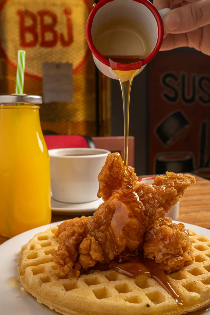 A crispy fried chicken served on top of a fluffy waffle, drizzled generously with maple syrup.