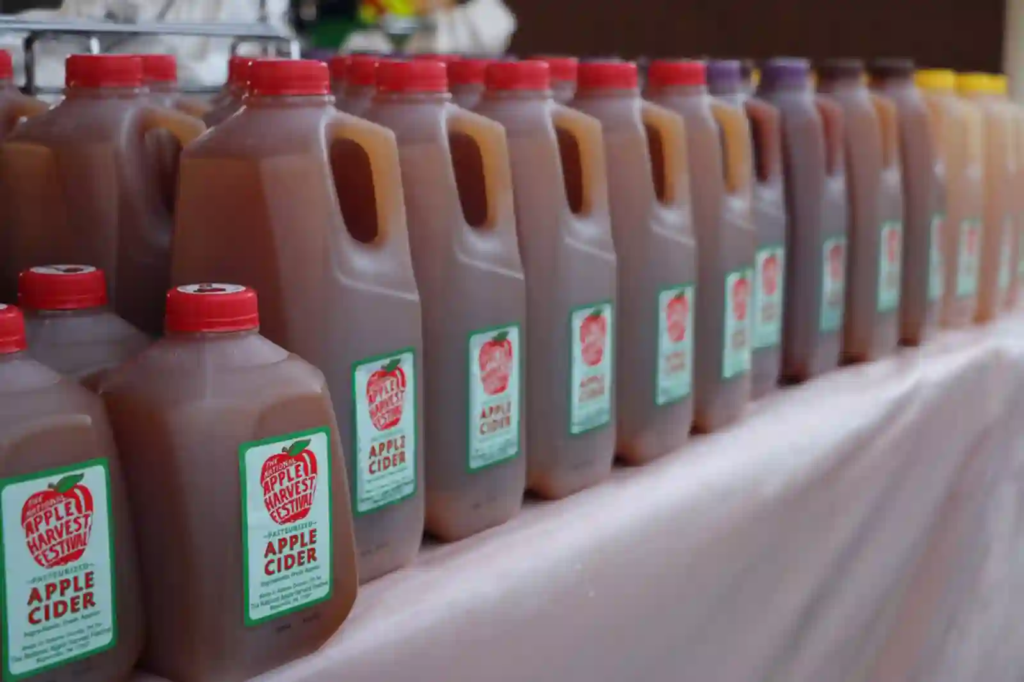 Row of apple cider jugs with festival labels.