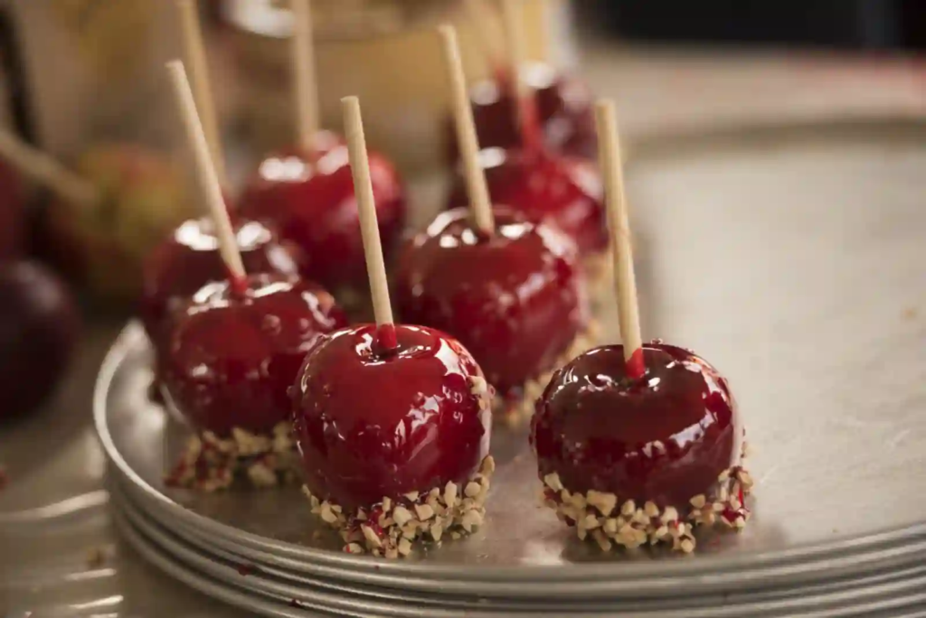 Red candy apples with chopped nuts on a tray