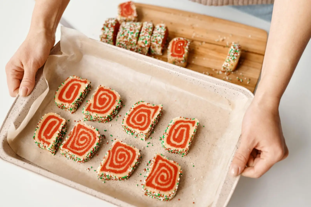 British Baking Show Biscuit Week slice-and-bake picture biscuits on a lined tray—red swirl cookies with sprinkle edges.